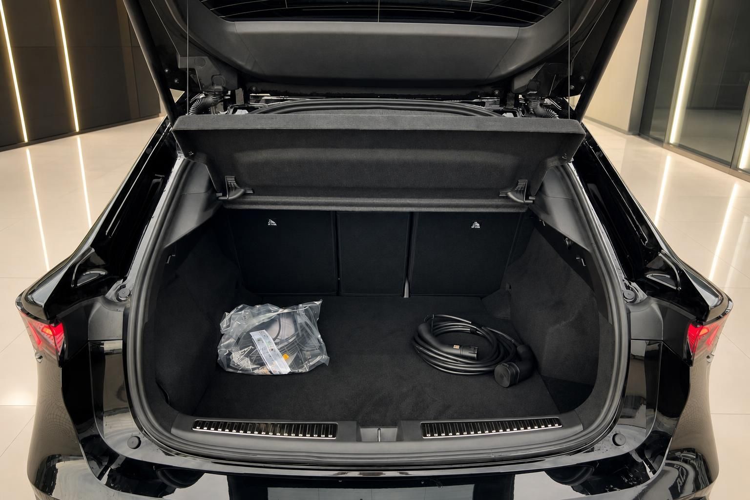 Kofferraum eines schwarzen Fahrzeugs mit Ladekabel und Zubehör