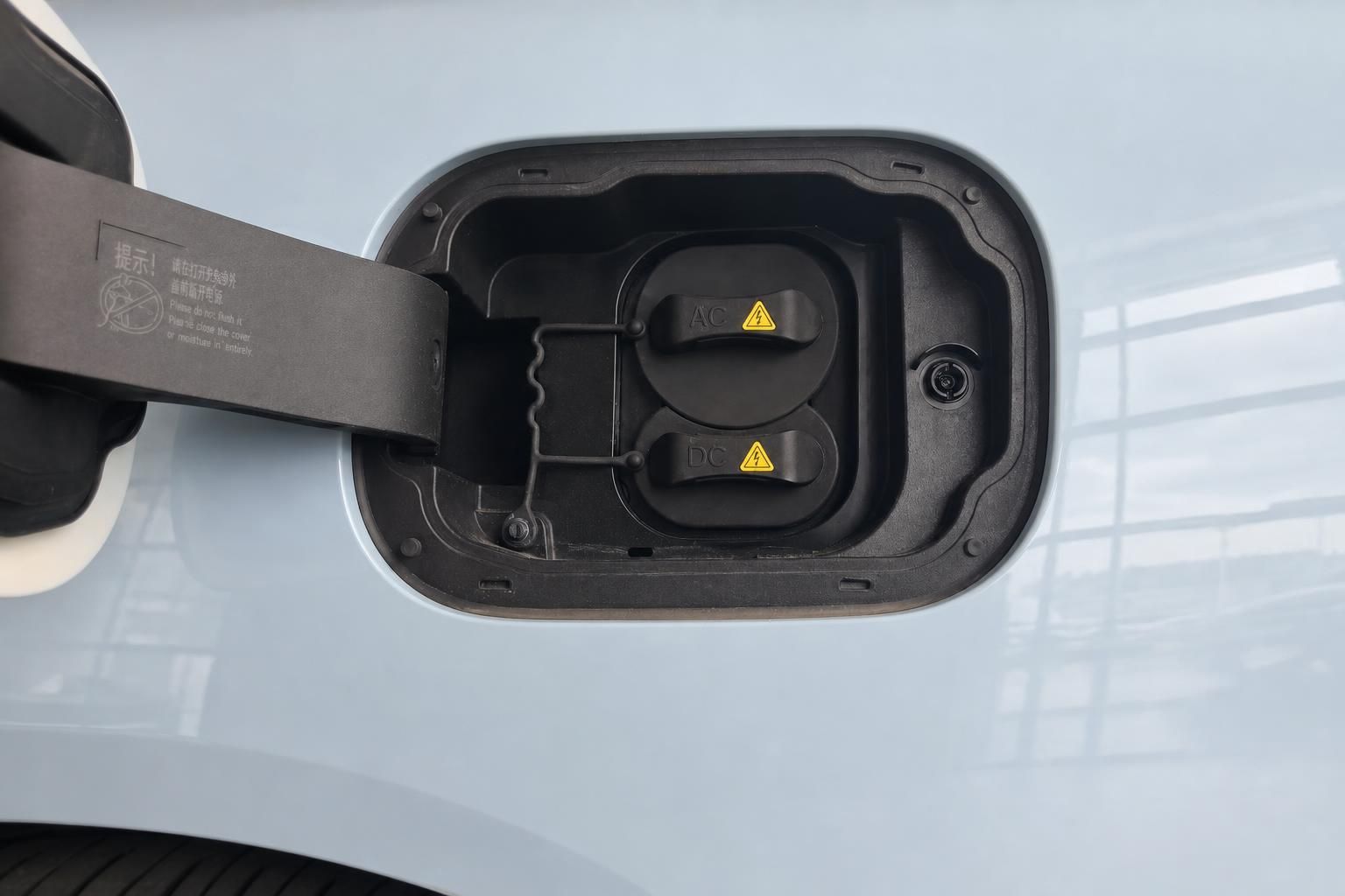 Elektrofahrzeug Ladeanschluss mit AC und DC Ladebuchsen an hellblauer Karosserie