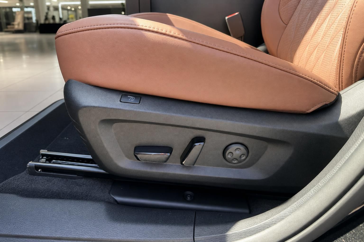 Fahrzeugsitz mit braunem Leder und elektrischer Sitzverstellung – Detailaufnahme Innenraum