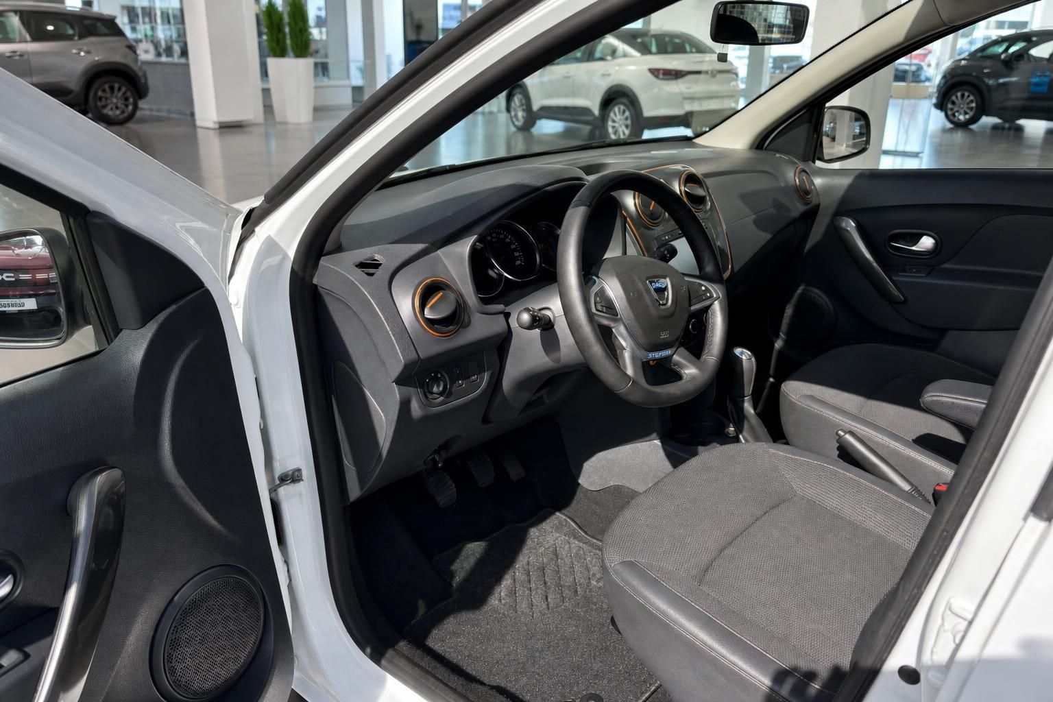 Dacia Sandero Innenraum mit grauem Cockpit, Multifunktionslenkrad und Stoffsitzen im Autohaus