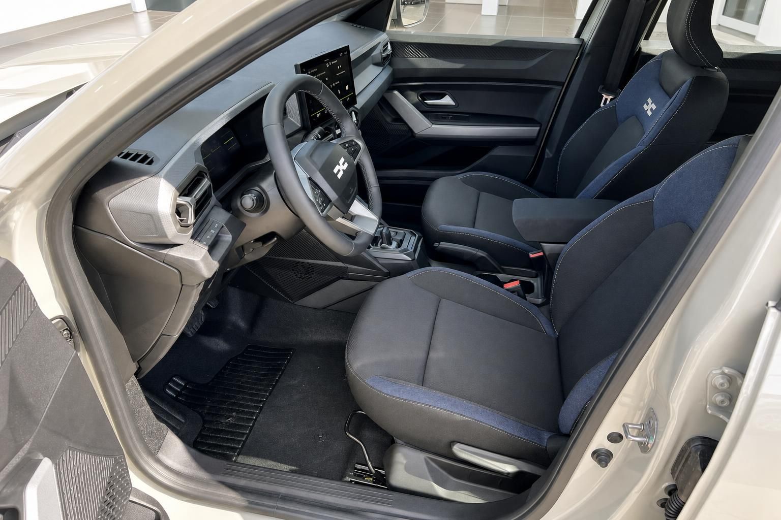 Dacia Duster Innenraum mit schwarzen Sitzen, Lenkrad und Mittelkonsole - Fahrersicht