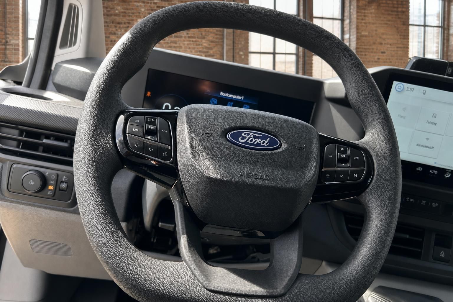 Ford Transit Lenkrad mit Multifunktionstasten, Airbag und digitalen Displays im Hintergrund