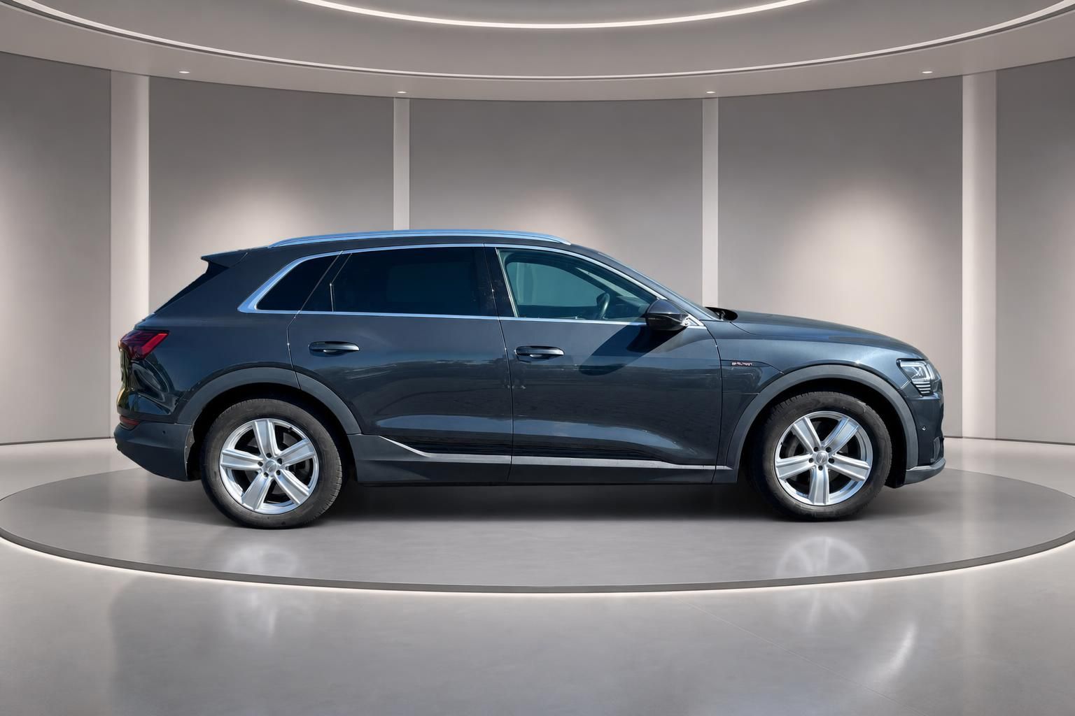 Audi e-tron Elektro-SUV Seitenansicht grau metallic auf Ausstellungsplattform im Showroom