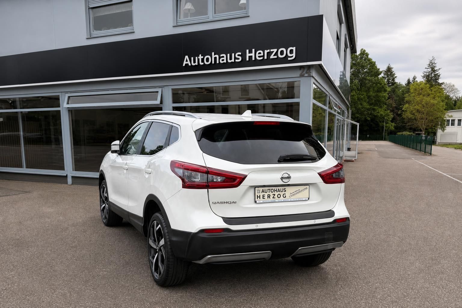 Nissan Qashqai weiß Heck schräg vor Autohaus Herzog