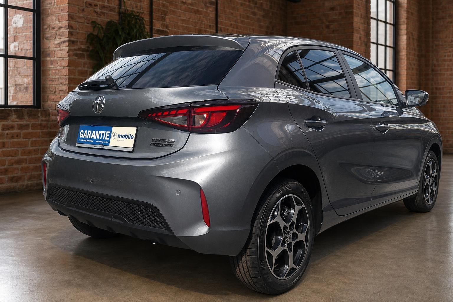 MG3 Hybrid+ grau, Heckansicht schraeg in Industrie-Ambiente