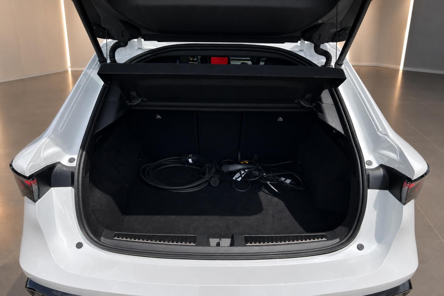 Geöffneter Kofferraum eines weißen Elektro-SUV mit Ladekabel im großen Gepäckraum
