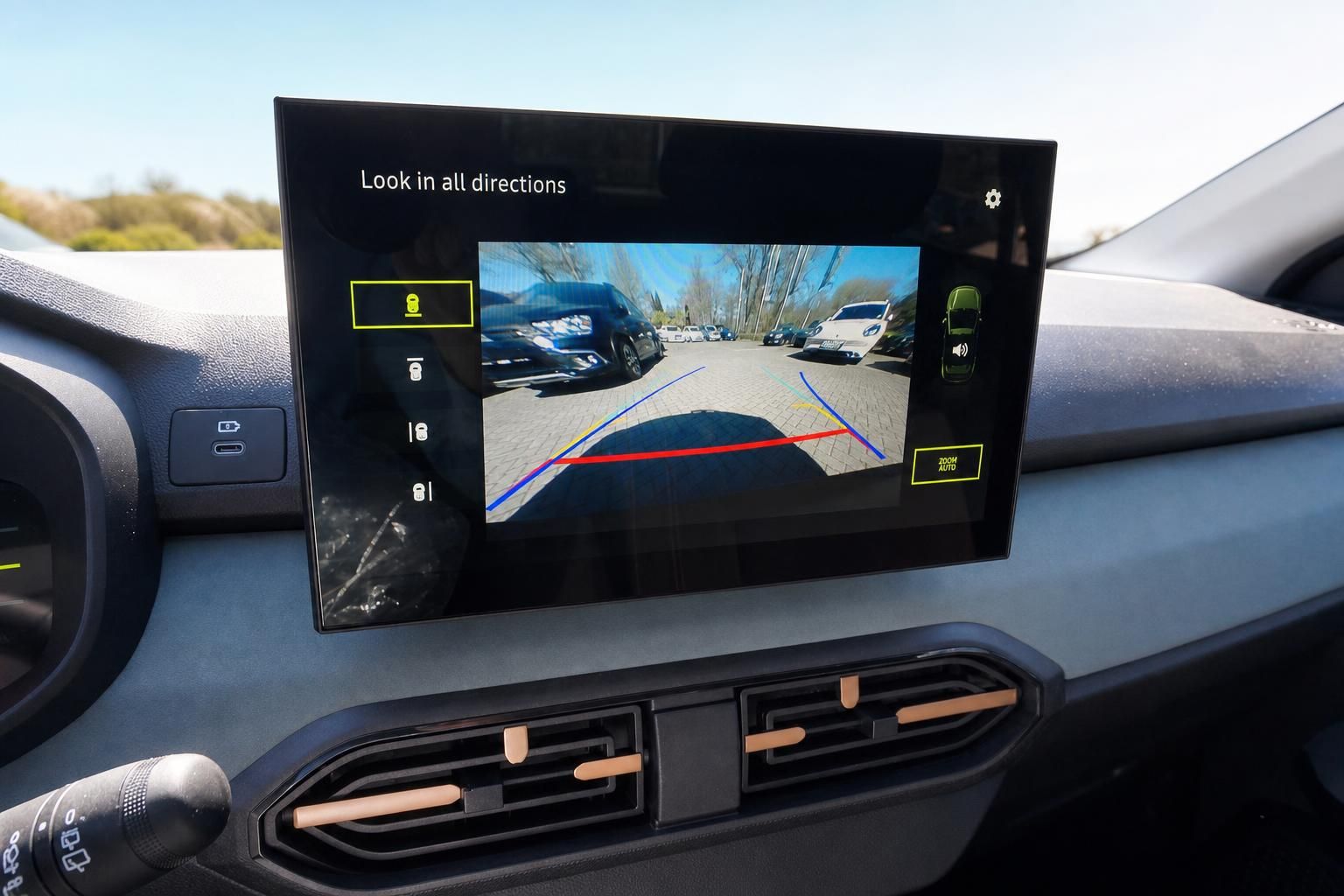 Infotainment-Bildschirm mit Rückfahrkamera und farbigen Einparklinien im Fahrzeuginnenraum