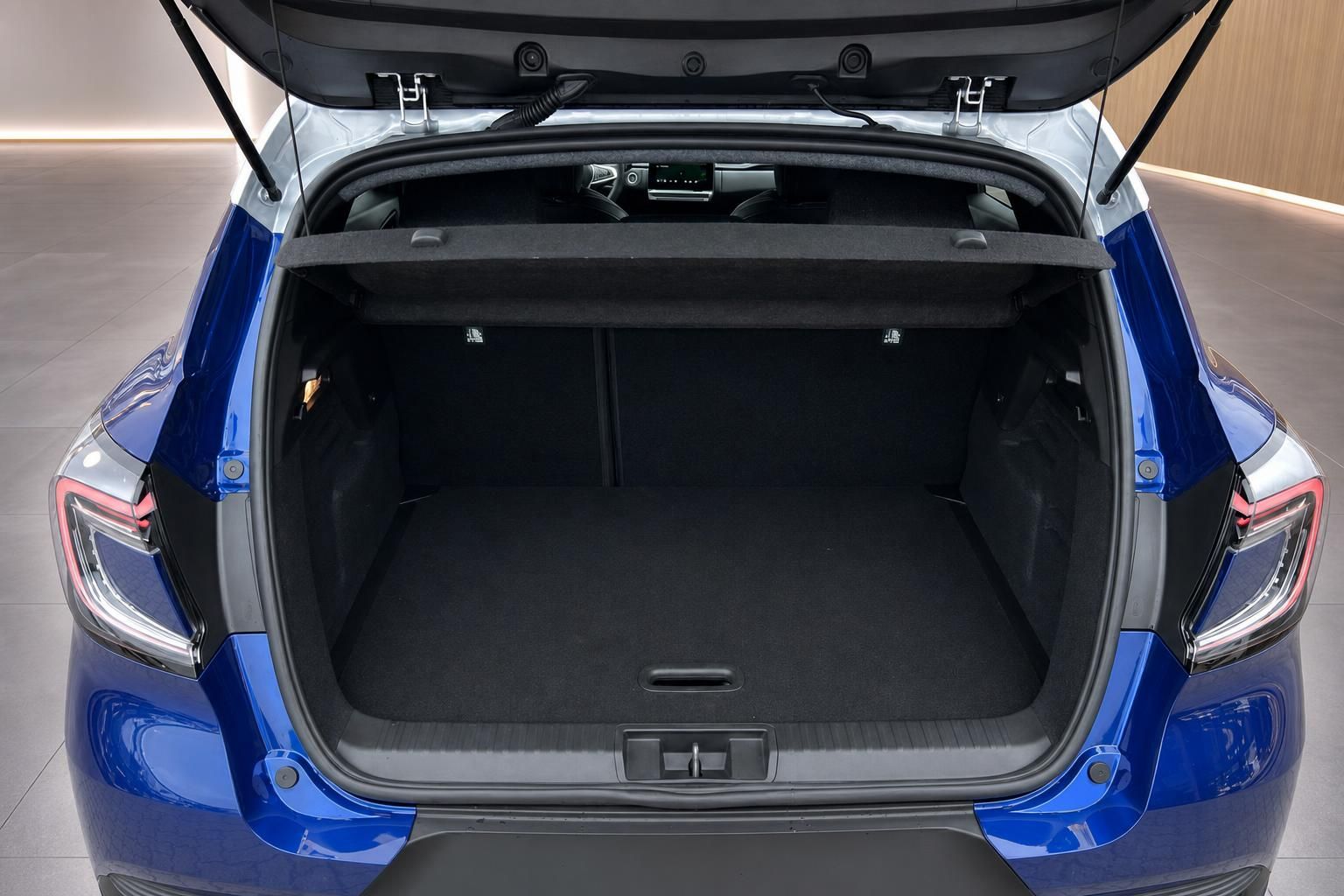 Offener Kofferraum eines blauen Fahrzeugs mit schwarzer Innenausstattung und geöffneter Heckklappe
