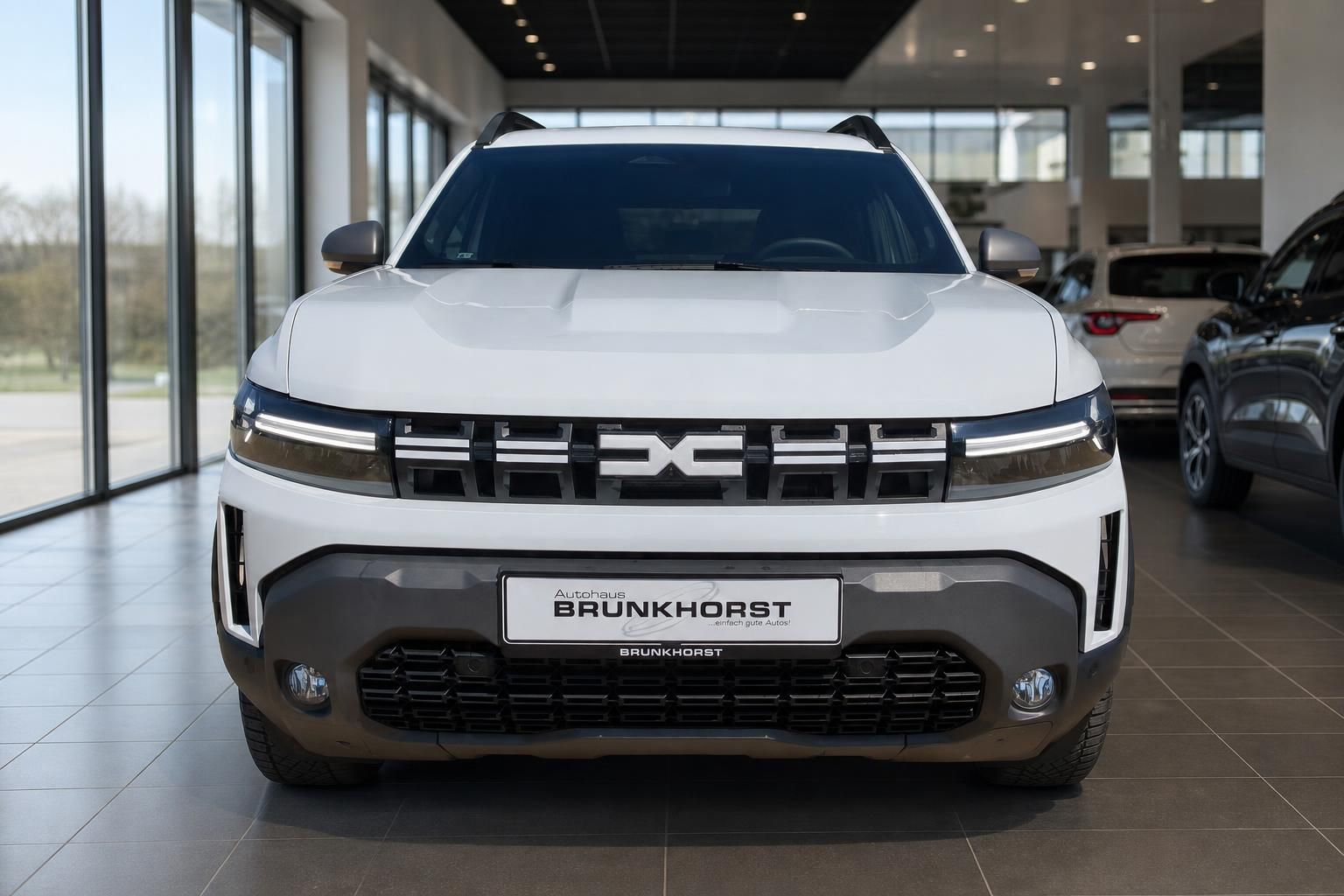 Dacia SUV Frontansicht weiß - LED-Scheinwerfer und markanter Kühlergrill im Showroom