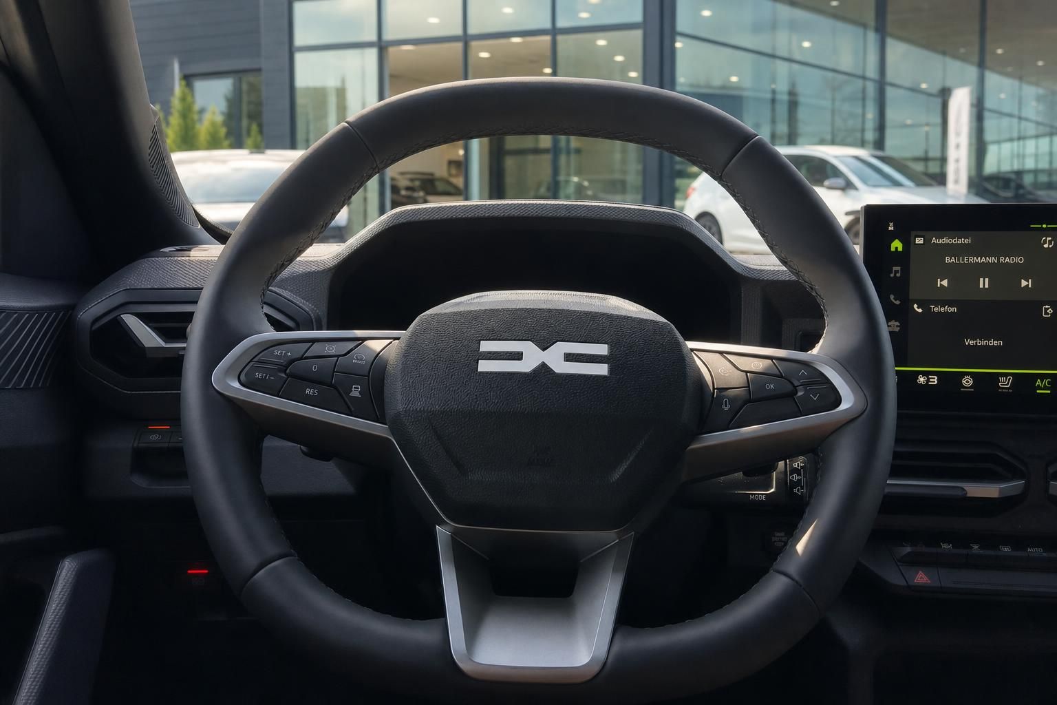 Dacia Lenkrad mit Multifunktionstasten und Infotainment-Display im modernen Fahrzeug-Cockpit