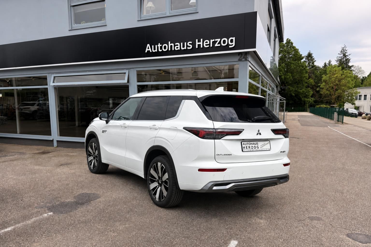 Weißer Mitsubishi Outlander SUV von hinten vor Autohaus Herzog - Gebrauchtwagen zum Verkauf