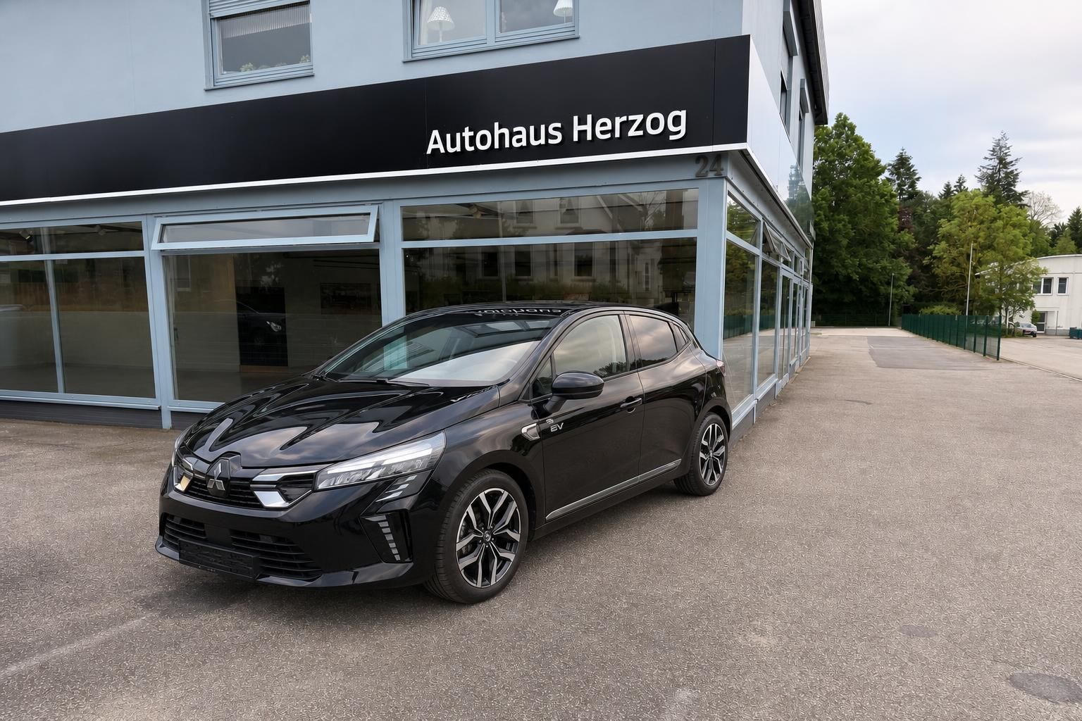 Schwarzer Mitsubishi Kompaktwagen vor Autohaus Herzog - Seitenansicht