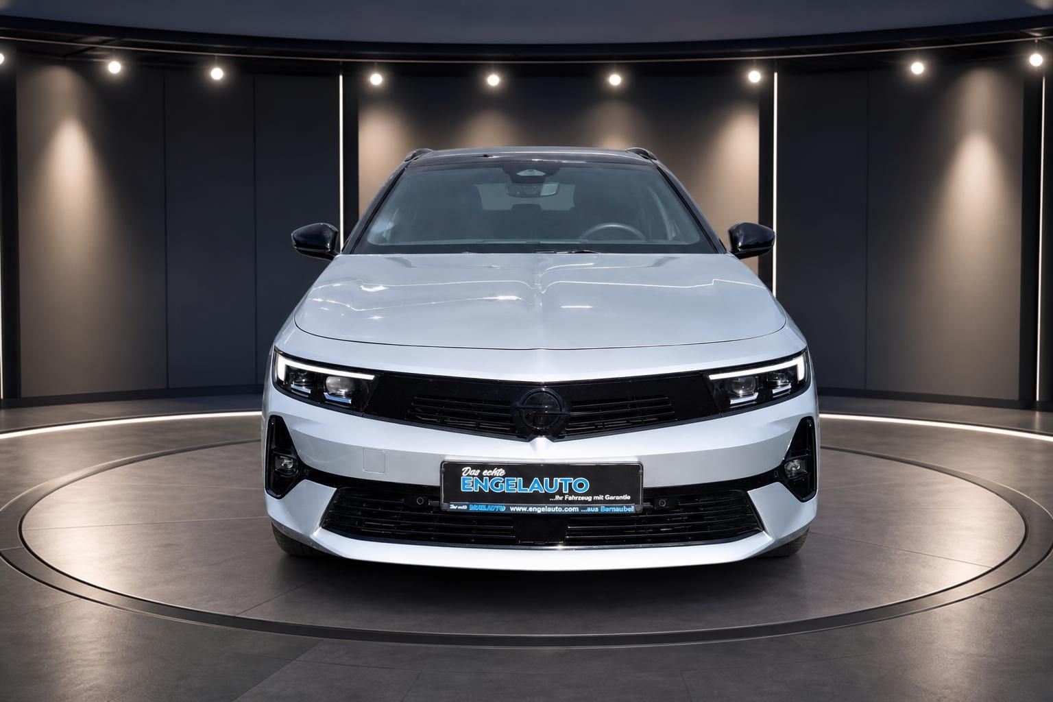 Opel Astra Kombi Frontansicht - weißes Fahrzeug mit markanter Kühlergrill und LED-Tagfahrlicht im Showroom