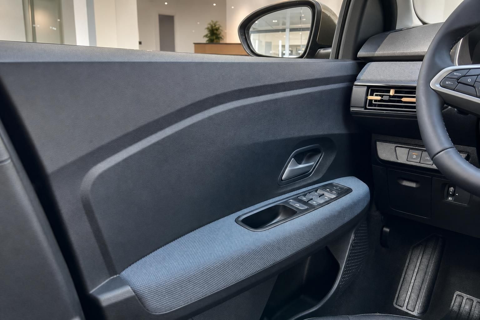 Türverkleidung mit Fensterhebern und Lenkrad im Fahrzeuginnenraum
