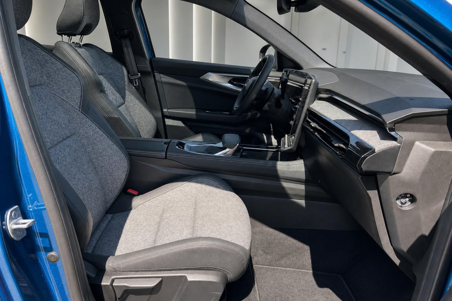 Innenraum eines blauen Fahrzeugs mit Blick auf Vordersitze und Cockpit