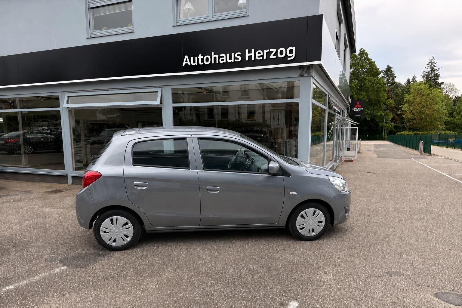 Mitsubishi Space Star in silber, Seitenansicht vor Autohaus Herzog