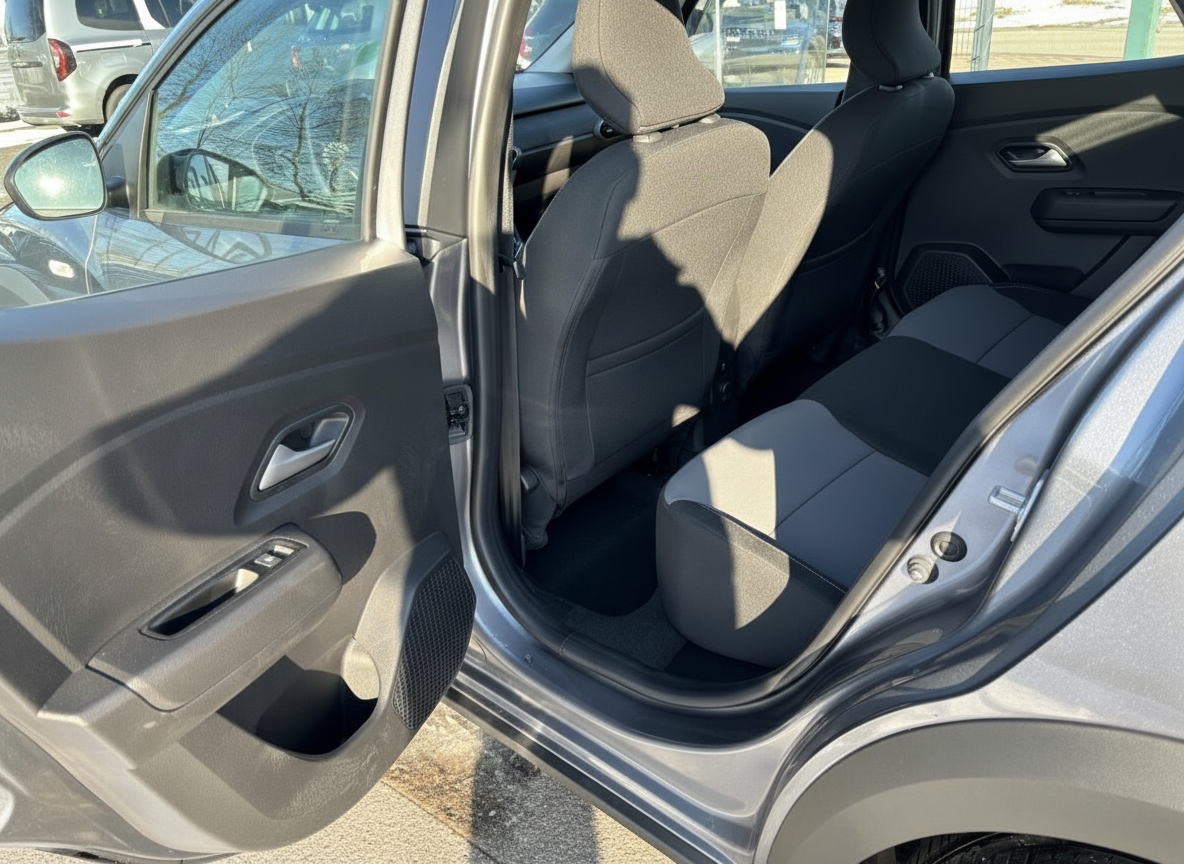 Grauer PKW Innenraum – hintere Sitzreihe mit schwarzen Stoffsitzen, geöffnete Beifahrertür