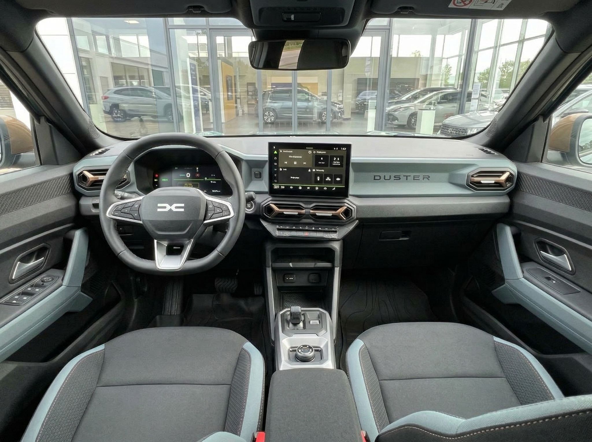 Dacia Duster Innenraum mit Lenkrad, Touchscreen und grauen Sitzen - Cockpit-Ansicht