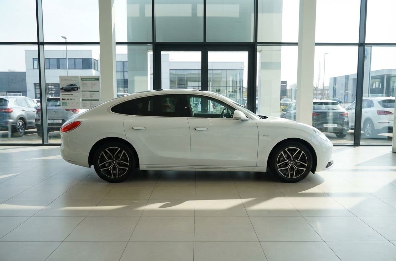 Weißer Luxus-Sedan in modernem Autohaus – Seitenansicht