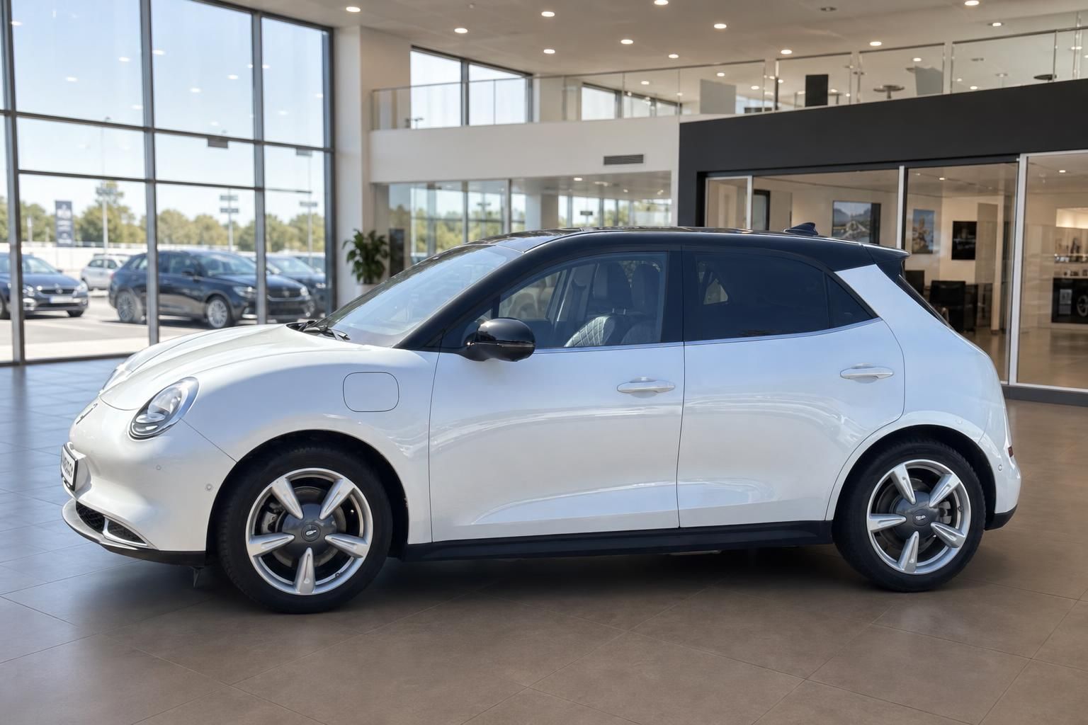 Weißer ORA Funky Cat Elektroauto, Seitenansicht links im modernen Autohaus mit großen Fensterfronten