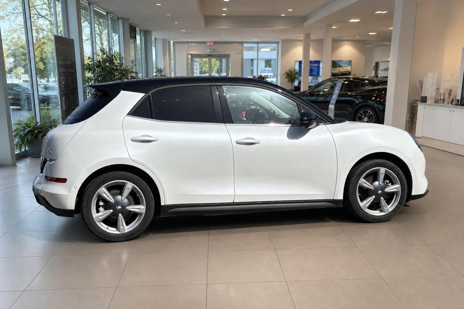 Weißer ORA Funky Cat mit schwarzem Dach, rechte Seitenansicht im hellen Autohaus-Showroom