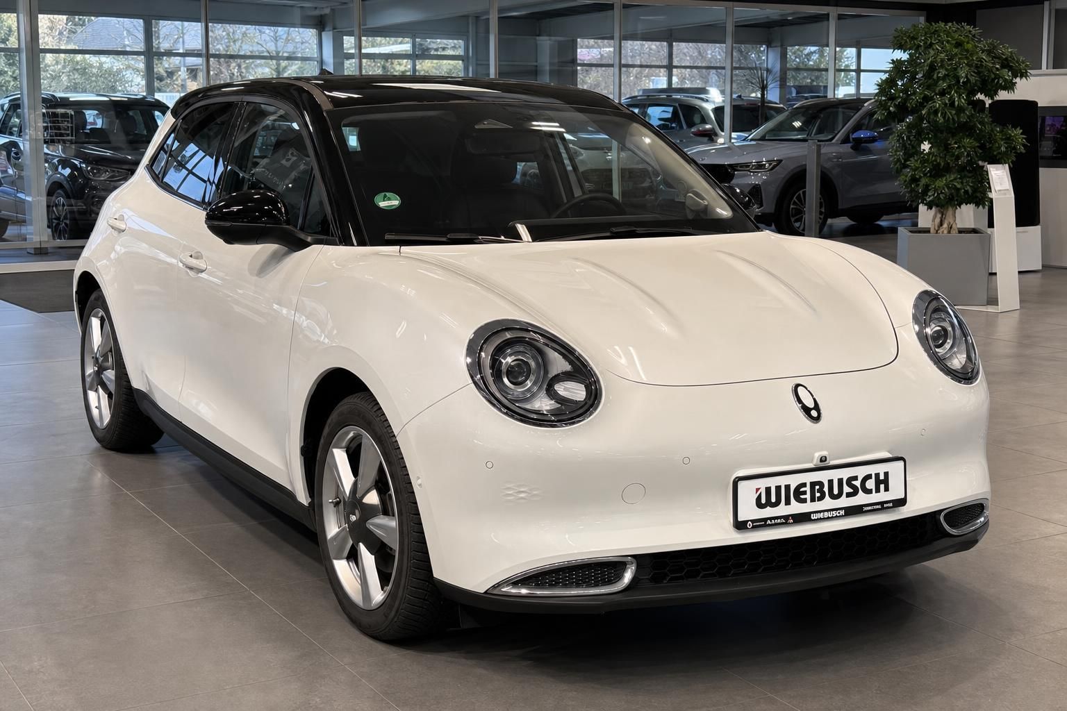 Weißer ORA Elektroauto Frontansicht schräg, runde Scheinwerfer und Händlerkennzeichen sichtbar