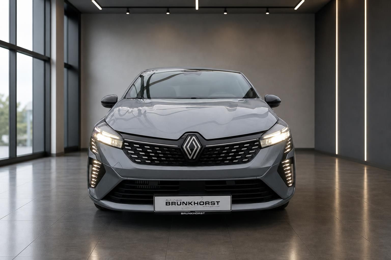 Renault Clio graue Frontansicht mit LED-Tagfahrlicht und Renault-Logo im Showroom