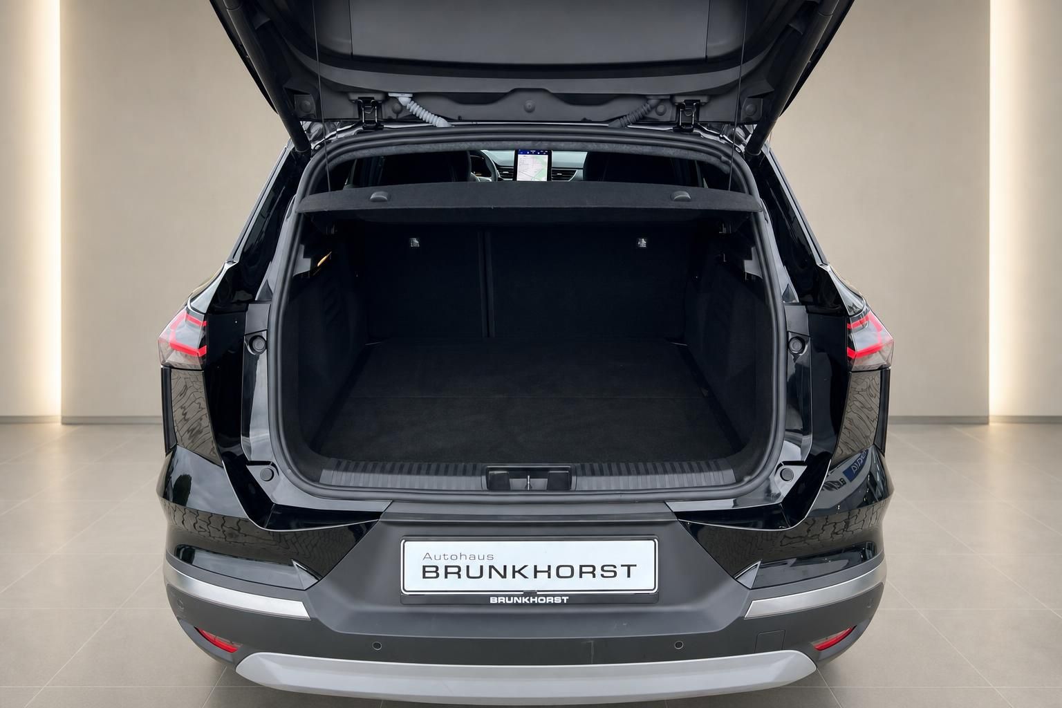 Geraeumiger Kofferraum eines schwarzen SUV mit geoeffneter Heckklappe