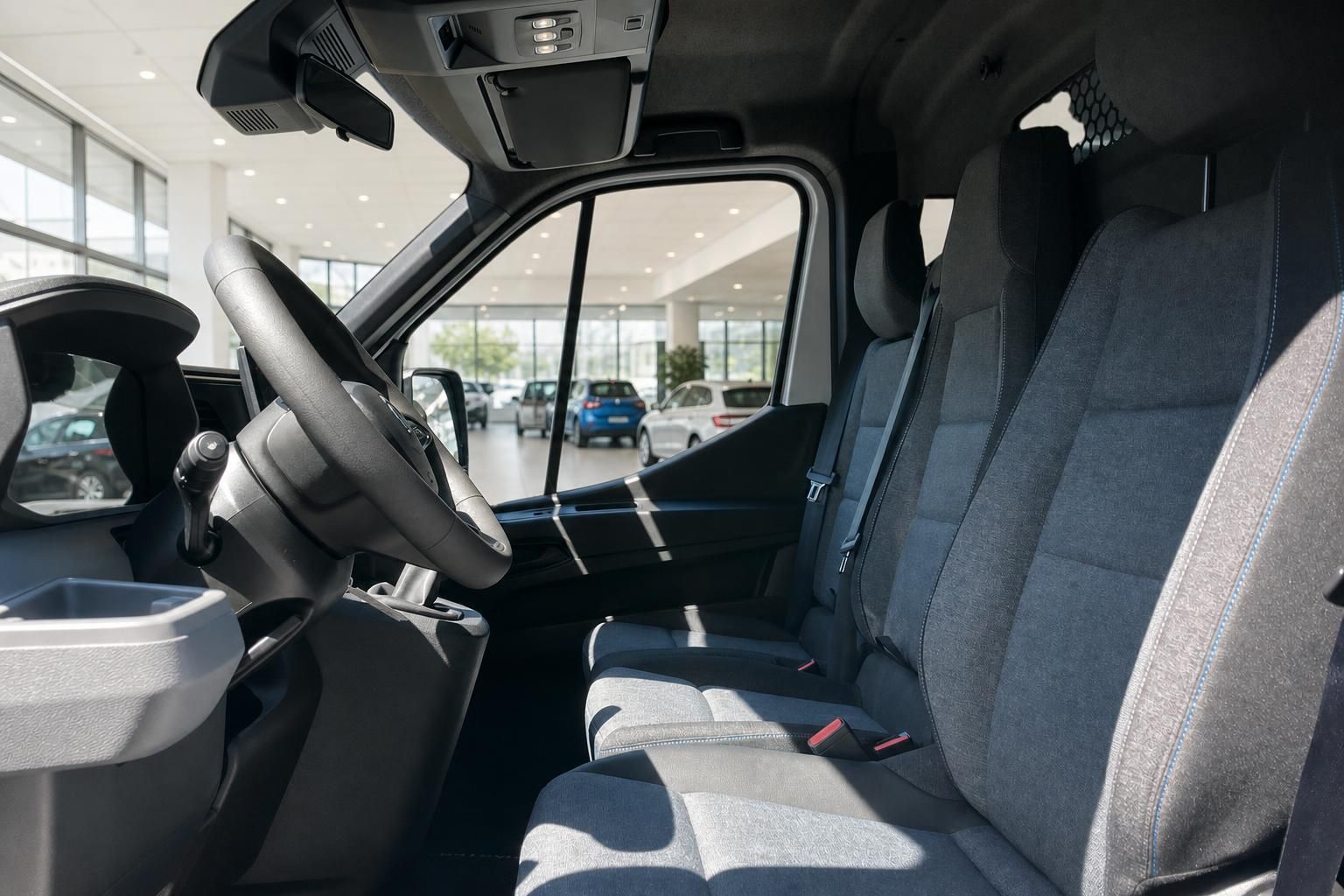 Transporter Fahrerplatz mit dunklen Stoffsitzen und Blick ins Autohaus