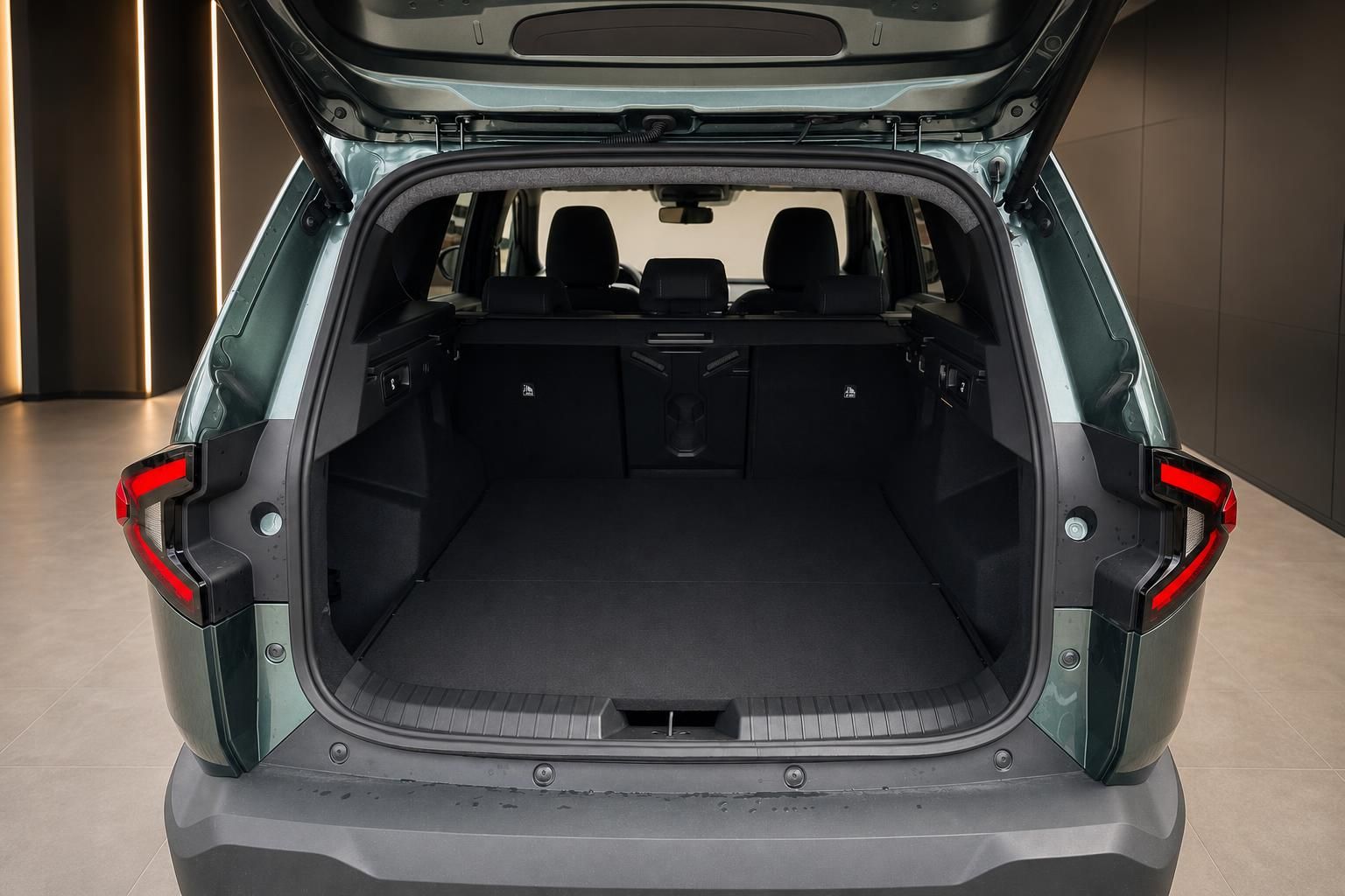 Geöffneter Kofferraum eines grünen SUV mit umgeklappten Rücksitzen und Ladeboden