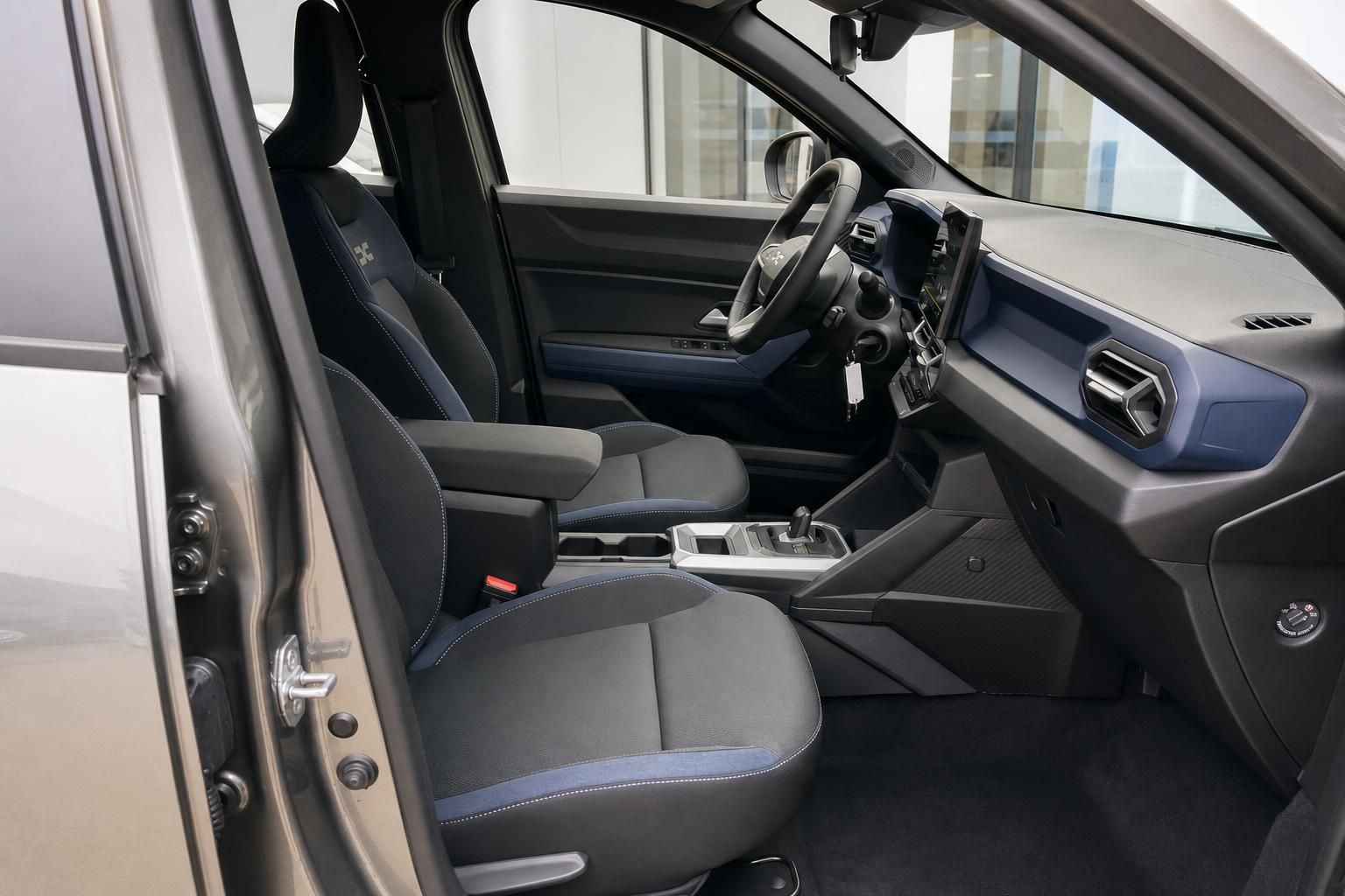 Dacia Innenraum Vordersitze schwarz-blau mit Mittelkonsole, Lenkrad und Armaturenbrett