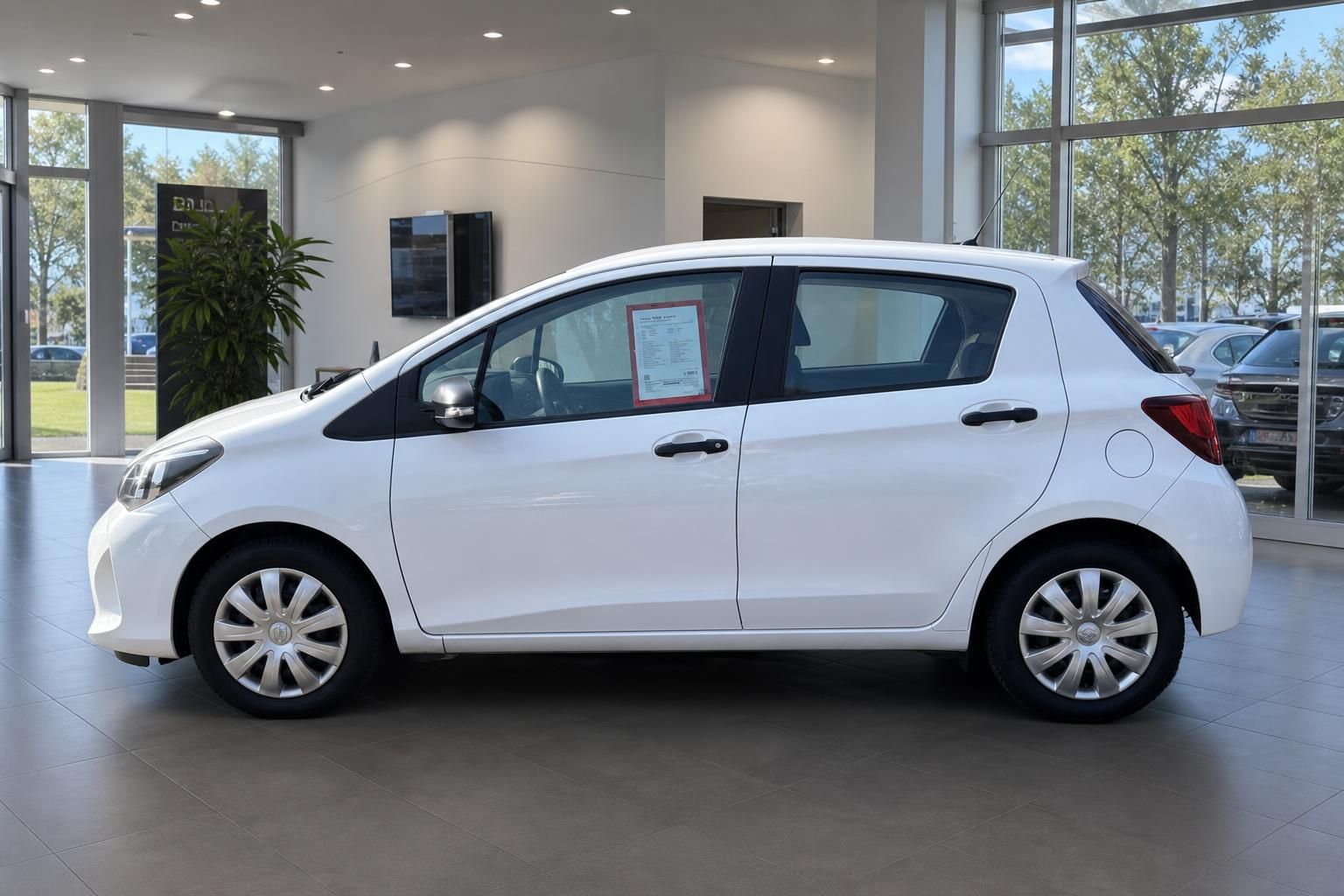 Weißer Toyota Yaris Seitenansicht im Autohaus mit Verkaufsinformationen am Fenster