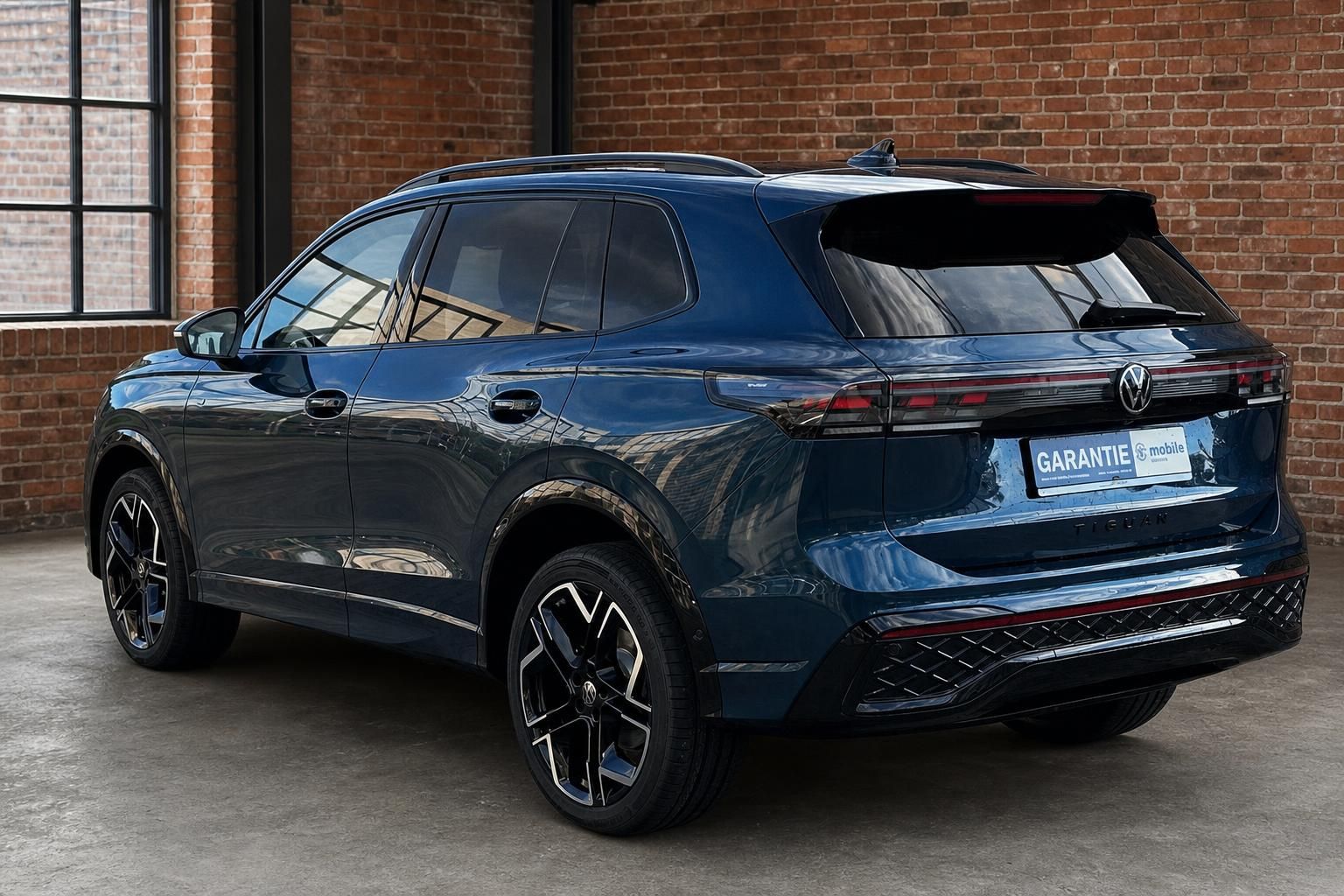 VW Tiguan dunkelblau Heckansicht seitlich in Loft-Ambiente