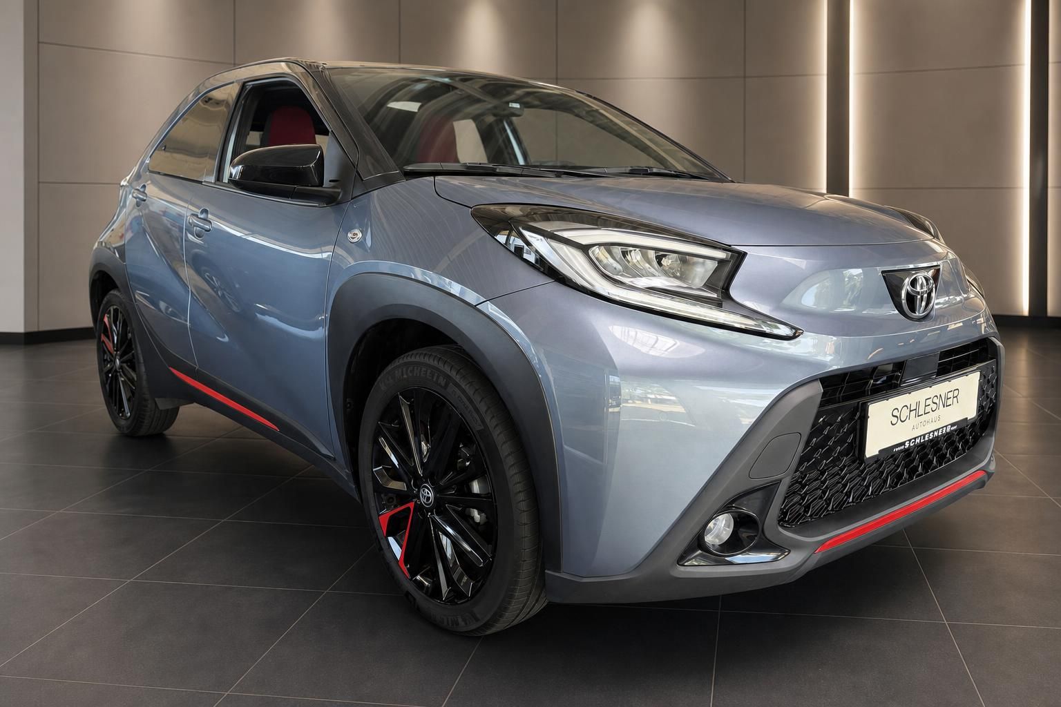 Toyota Aygo X in Blau-Grau, Frontansicht im Showroom