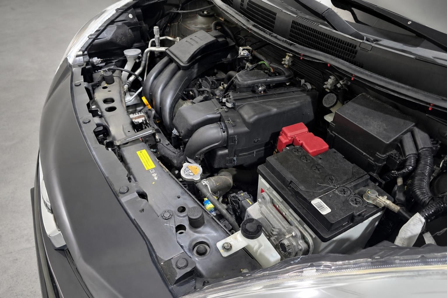 Motorraum eines Nissan mit Batterie und Anschlüssen im Detail