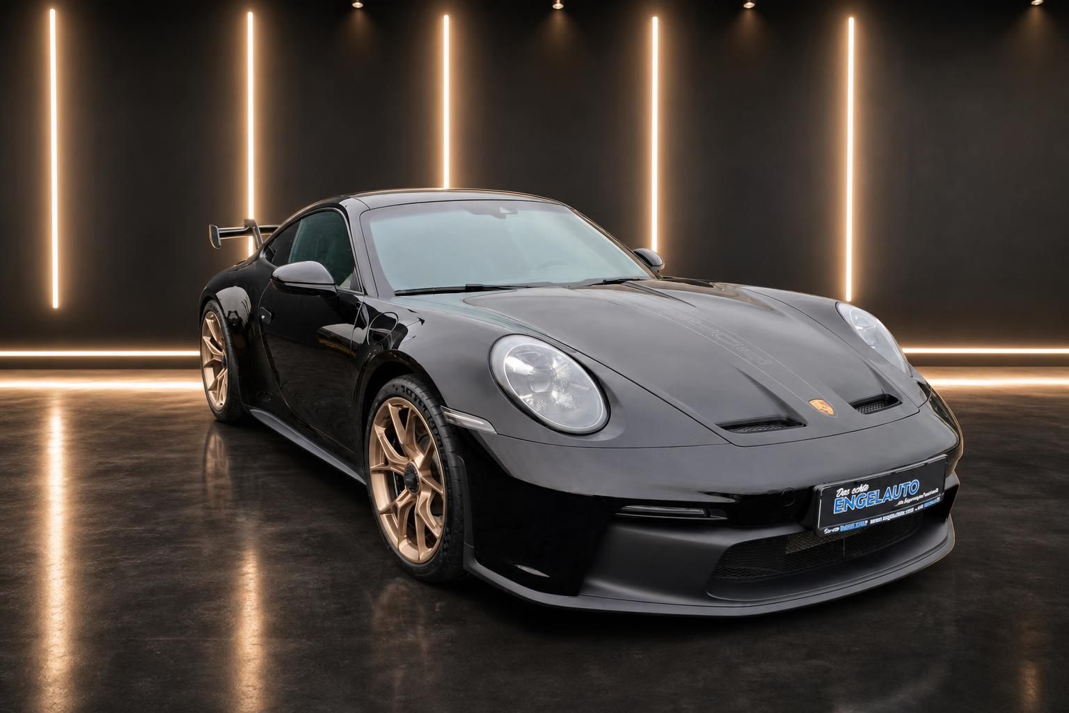 Schwarzer Porsche 911 GT3 Sportwagen mit goldenen Felgen in moderner Showroom-Beleuchtung