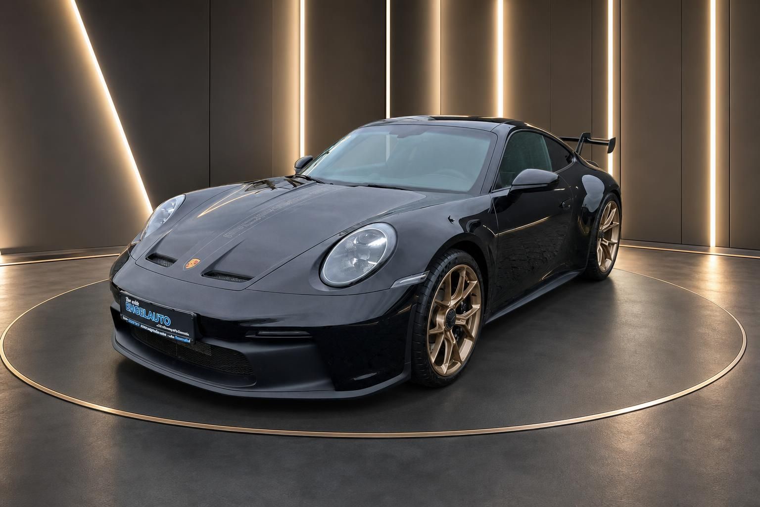 Schwarzer Porsche 911 GT3 Schrägansicht vorne links mit goldenen Speichenfelgen im Showroom
