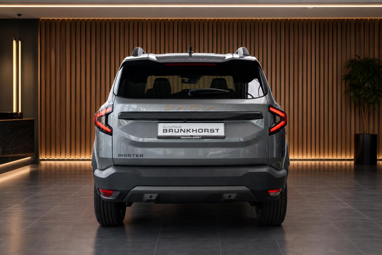 Dacia Bigster Heckansicht in grau mit LED-Rückleuchten und Dacia-Schriftzug im Autohaus Showroom