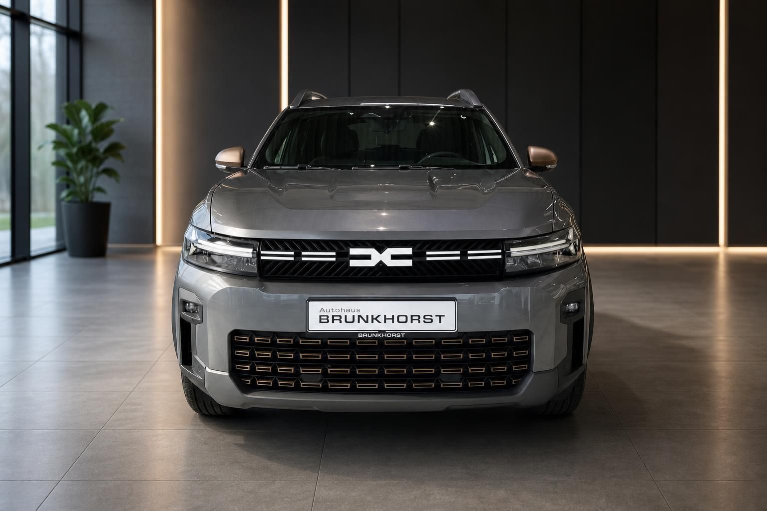 Dacia SUV Frontansicht in grau mit markanter Kühlergrillgestaltung und LED-Scheinwerfern im Showroom