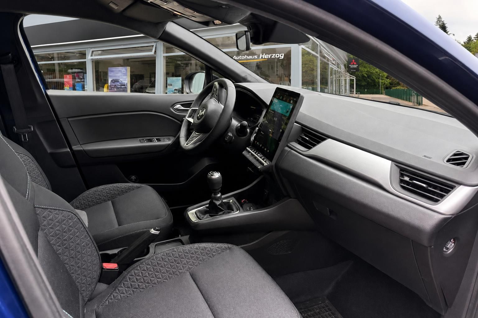 Fahrzeuginnenraum mit schwarzem Armaturenbrett, Touchscreen-Display und Stoffsitzen