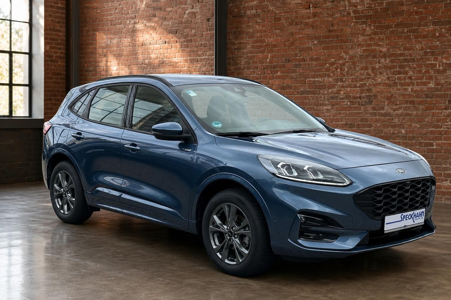 Ford Kuga blau Frontansicht schraeg vor Backsteinwand