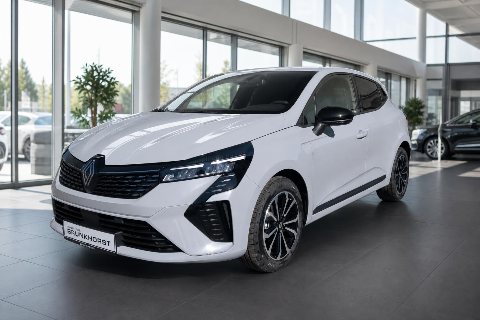 Weißer Renault Clio in modernem Autohaus-Showroom mit Panoramafenstern