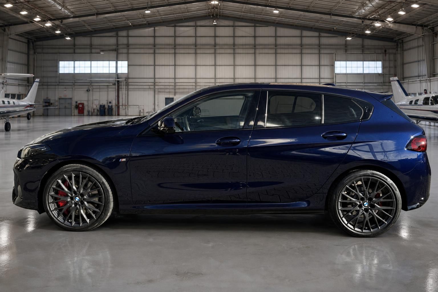BMW 1er M Performance - Seitenansicht in dunkelblau mit schwarzen Sportfelgen im Hangar