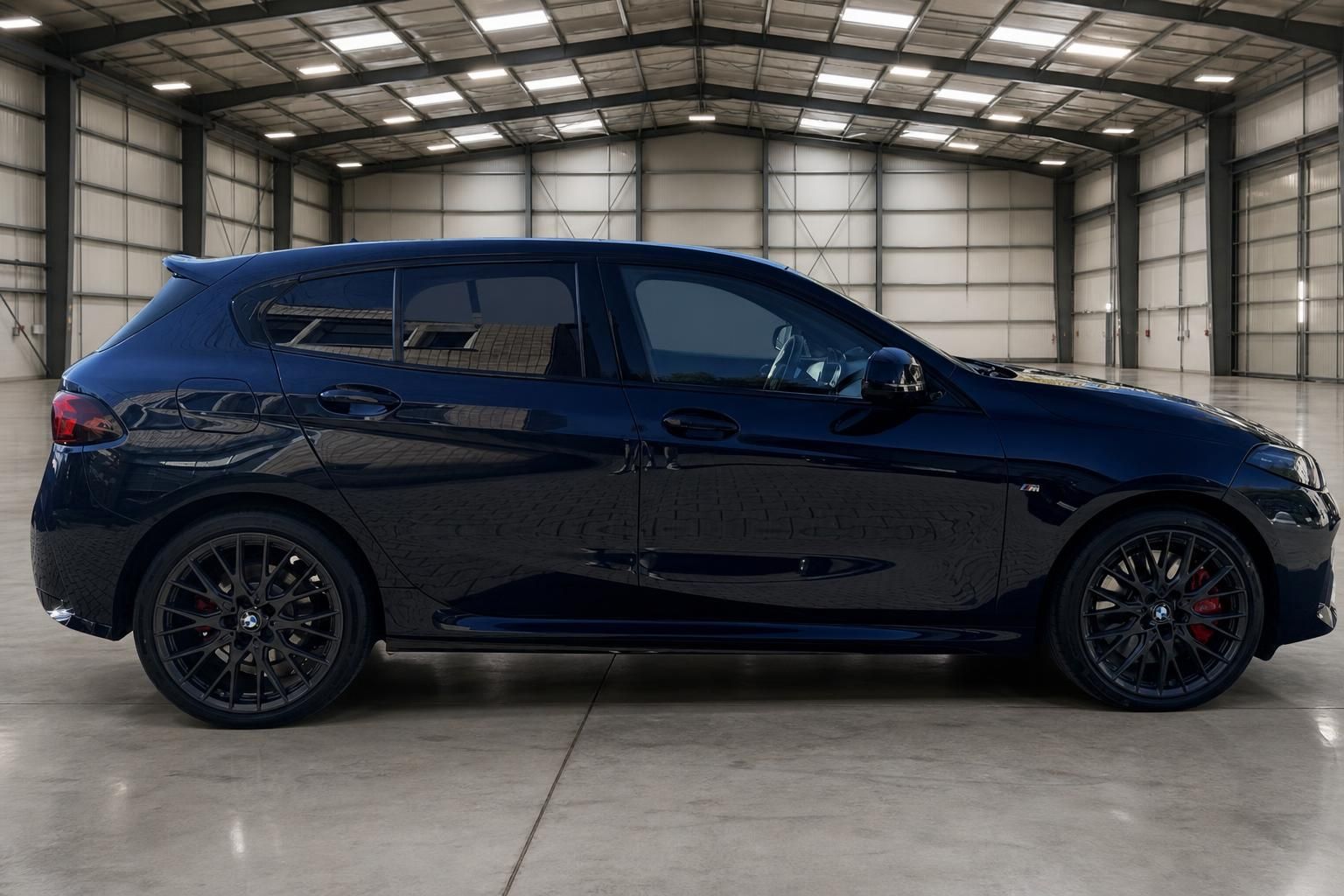 BMW 1er Seitenansicht rechts - dunkelblauer Kompaktwagen mit M-Performance Felgen im Hangar