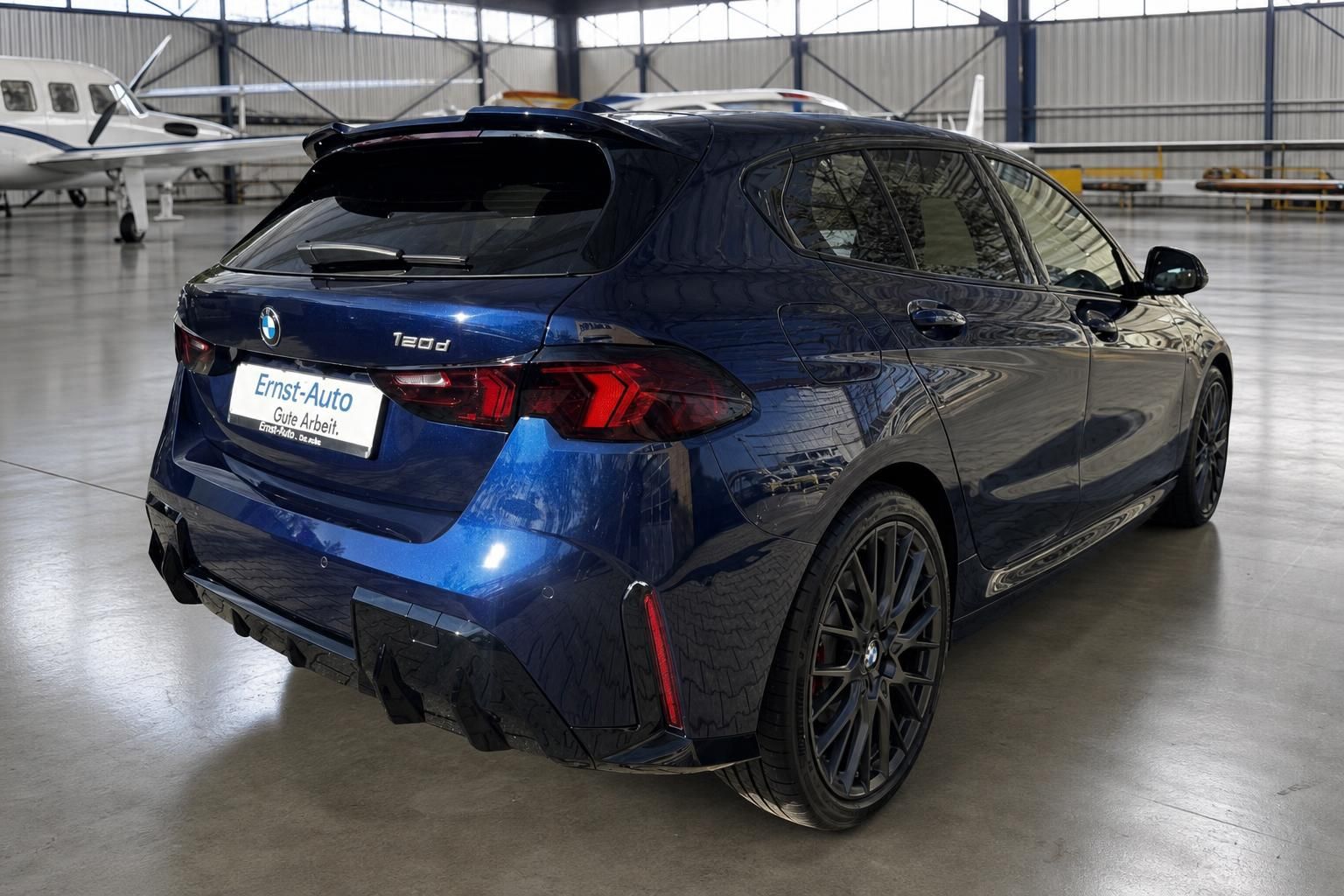 BMW 1er Heckansicht - dunkelblau metallic mit LED-Rücklichtern und Sportauspuff im Hangar