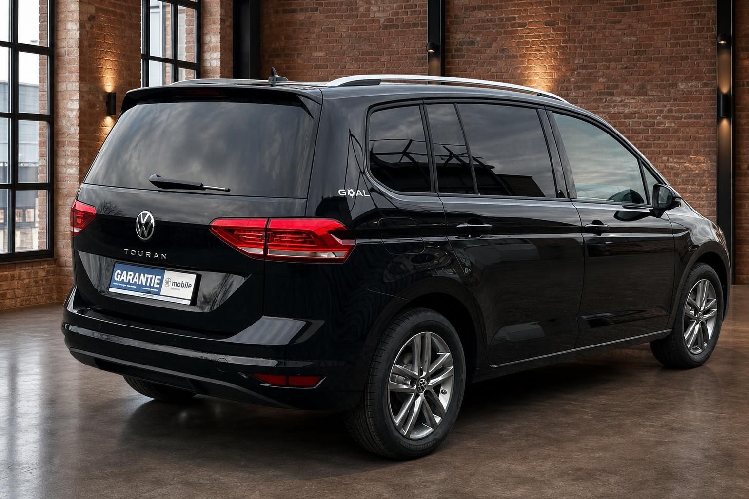 VW Touran schwarz Heck seitlich vor Backsteinmauer