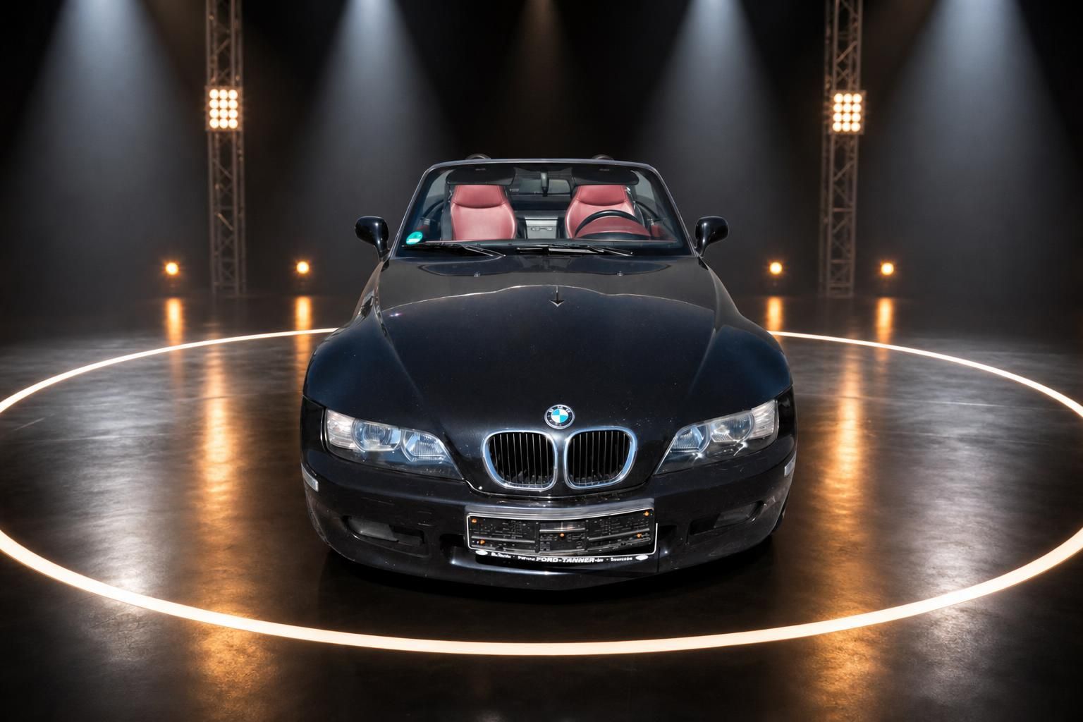 BMW Z3 Roadster schwarz offenes Verdeck Frontansicht mit rotem Interieur im Showroom