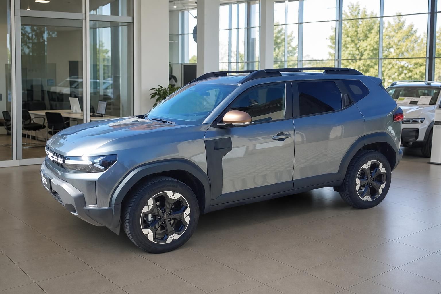 Grauer Dacia Duster SUV im Autohaus - Seitenansicht von links mit modernen Leichtmetallfelgen