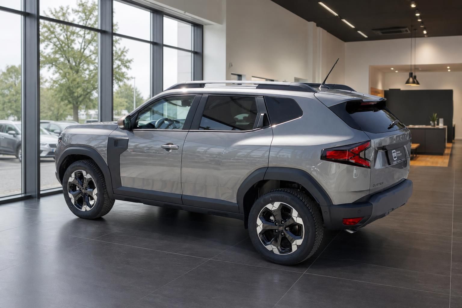 Dacia Duster SUV in graumetallic, Schrägansicht hinten rechts im Autohaus-Showroom