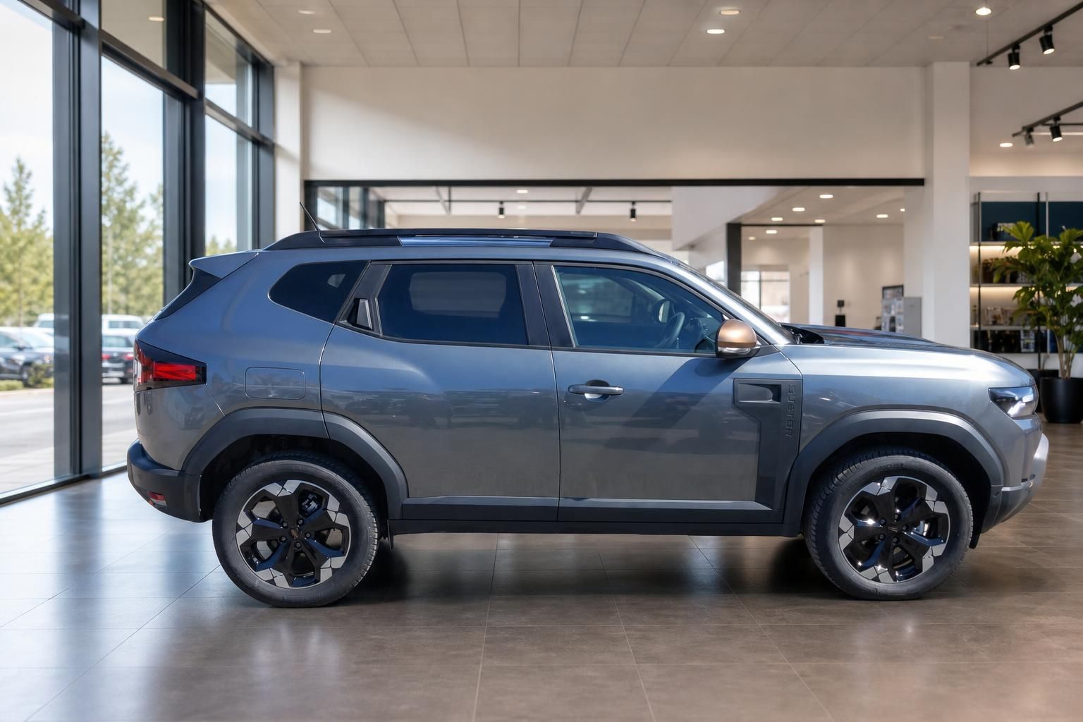 Dacia Duster SUV in grau, Seitenansicht von links im modernen Autohaus-Showroom